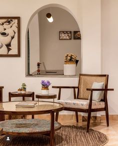 a living room with two chairs and a coffee table in front of a mirror on the wall