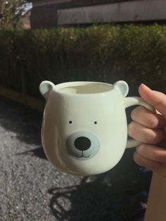 a hand holding a mug with a bear face on it