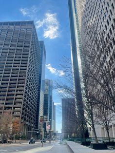 two tall buildings next to each other on a street with trees in the foreground