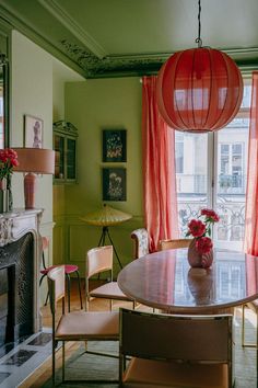 a dining room table and chairs in front of a fire place with red lanterns hanging from the ceiling