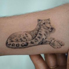 a hand with a tattoo on it that has a snow leopard sitting on the arm