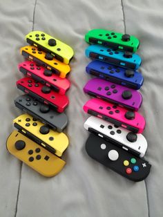 several different colored nintendo wii controllers on a bed