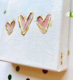 three heart shaped studs sitting on top of a white paper covered box with polka dots