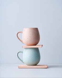 three cups stacked on top of each other in different colors and shapes, one with a wooden handle