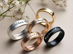 four different types of wedding rings with names on them and flowers in the foreground