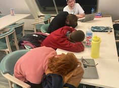 three people sitting at a table working on laptops