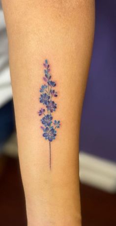 a small blue flower tattoo on the right thigh and lower leg, with purple flowers growing out of it