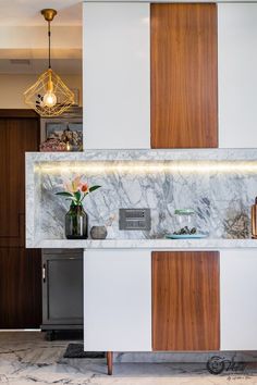 a kitchen with marble counter tops and wooden cabinets in the center, along with lights above