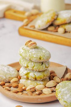 almond cookies stacked on top of each other in a wooden plate with nuts around them