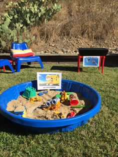 there is a sandbox with toys in it on the grass