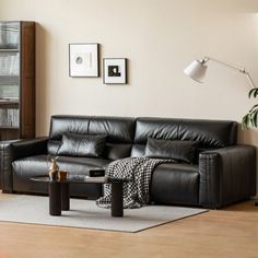 a black leather couch sitting on top of a hard wood floor next to a table