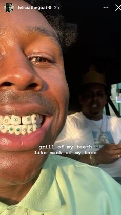 a man with braces on his teeth smiles at the camera while another man sits behind him