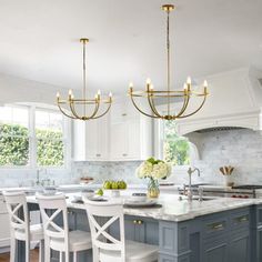 a kitchen with an island, chandelier and marble counter tops