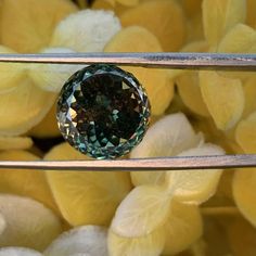 a green diamond sitting on top of a metal rack next to some yellow flowers and leaves