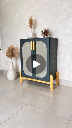 a black and yellow cabinet sitting on top of a tile floor next to a vase