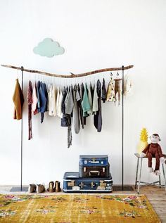 a room with luggage and clothing hanging on the clothes line, next to a rug