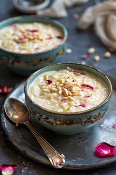 two bowls filled with oatmeal on top of a metal plate next to spoons