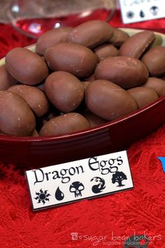 a bowl filled with chocolate eggs on top of a red table cloth next to other items