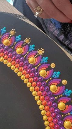 a person is holding a skateboard painted with colorful designs on it's side