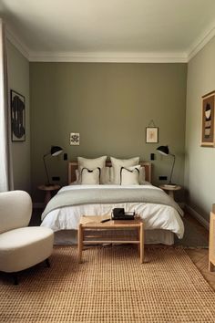 a bed sitting in a bedroom next to a white chair and table on top of a rug