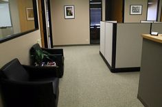 an office cubicle with two black chairs and a plant in the corner next to it