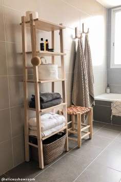 a bathroom with a ladder shelf next to the bathtub and towels on the rack