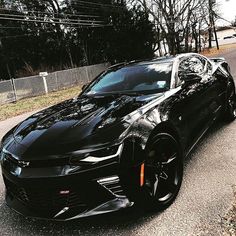 a black chevrolet camaro is parked on the street