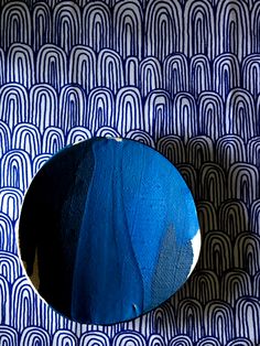 a round blue object sitting on top of a patterned wallpaper covered in white circles