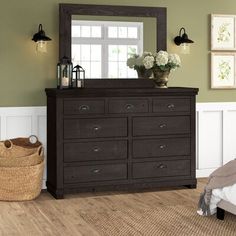 a bedroom with a dresser, mirror and basket on the floor in front of it