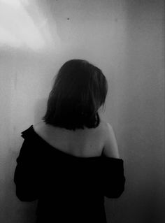 a woman standing in front of a wall with her back turned to the camera,