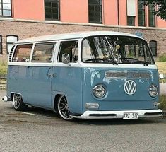 an old blue vw bus parked in front of a brick building