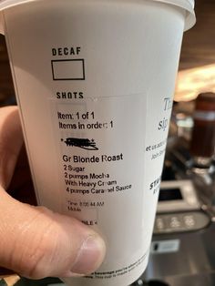 a person holding up a coffee cup with the label on it's side, which reads decaf shots