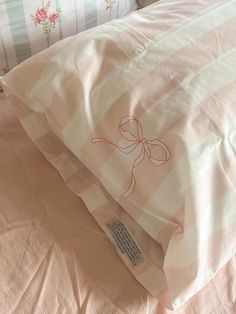 a bed with pink and white sheets, pillows and a tag on the pillow case