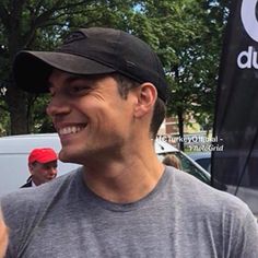 a man is smiling and holding up his cell phone in front of other people on the street