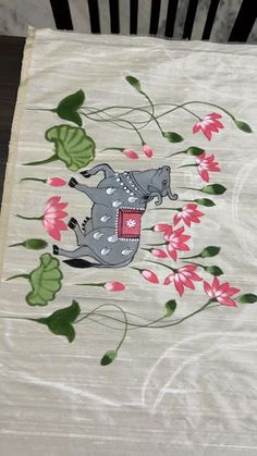 an elephant is sitting on top of a table cloth with flowers and leaves around it