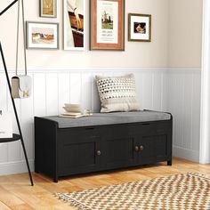 a black bench sitting on top of a hard wood floor next to a white wall