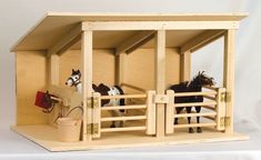 two miniature horses in a wooden stable on a white tableclothed surface, with one horse looking over the fence