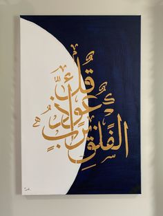 a painting with arabic writing on it in a white and blue frame hanging on a wall