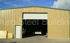 two cars are parked in front of a metal building with the doors open and one is empty