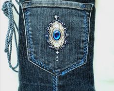 the back pocket of a pair of jeans with a blue jeweled brooch on it