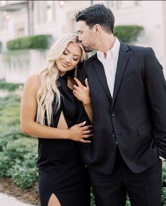 a man and woman in formal wear standing next to each other with their arms around one another