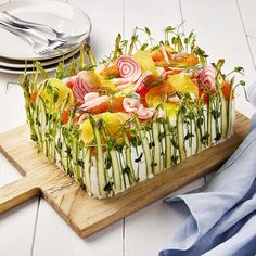 a cake with vegetables on it sitting on top of a cutting board next to plates