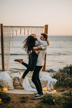 a man and woman hug each other in front of an altar by the ocean at sunset