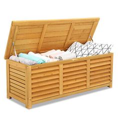 a wooden storage box filled with blankets and pillows