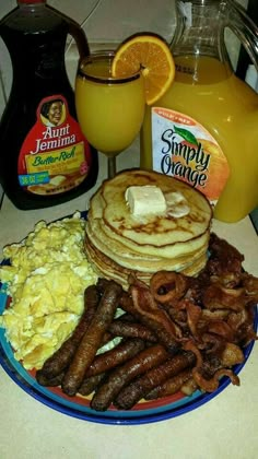 breakfast plate with eggs, sausages, pancakes and orange juice