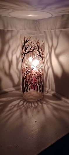 a candle is sitting on a table with the shadow of trees