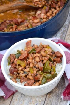 a bowl filled with beans and rice next to a blue casserole dish on a wooden table