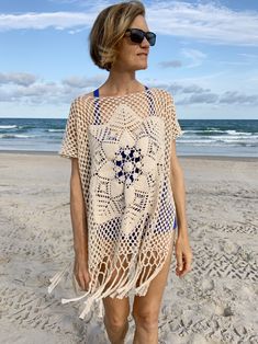 a woman standing on the beach wearing a crochet ponchy coverup