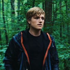 a young man standing in the middle of a forest