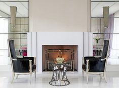 a living room filled with furniture and a fire place in front of a mirror wall